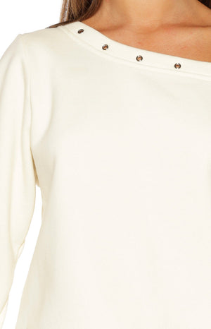 Close-up of the cream sweater's asymmetric neckline with a row of silver eyelets