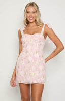 blonde model wearing a pink floral mini dress with tie strap details