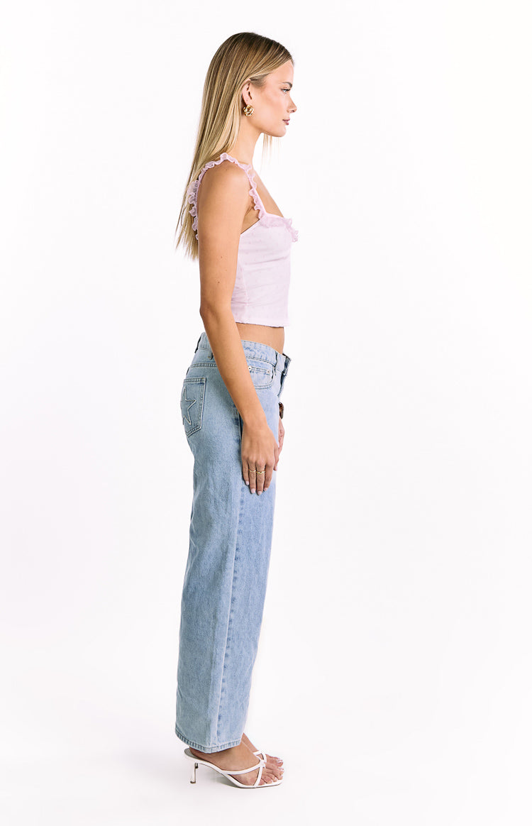 Side view of a pink and white polka dot frill top with ruffled straps and a cropped hem