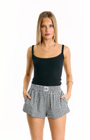 A comfortable yet stylish outfit featuring a white ribbed scoop-neck tank top and black and white gingham print shorts with an elasticated waist.