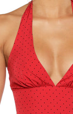 Close-up of the deep V-neckline and gathered bust detail of a red polka dot halter neck top