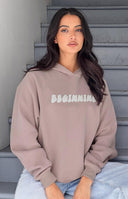 Front view of the cropped beige hoodie with white BEGINNING text, raglan sleeves, and ribbed cuffs