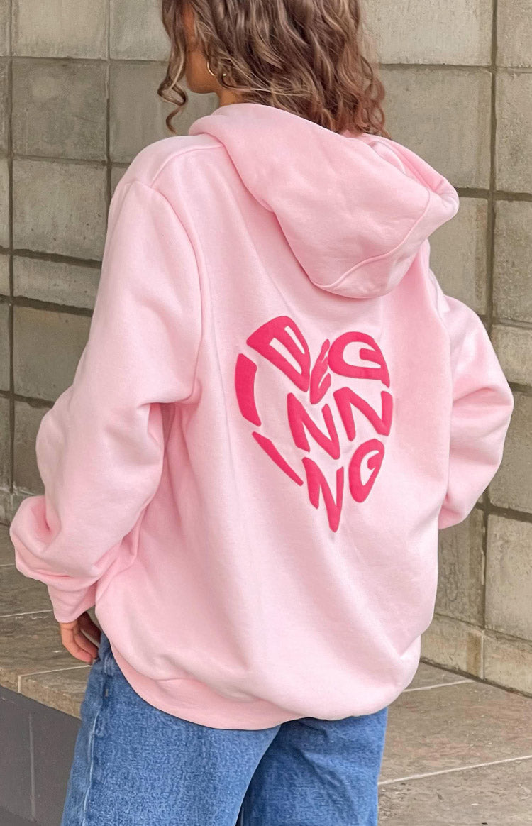 Back view of a light pink oversized hoodie featuring a large hot pink heart graphic on the back