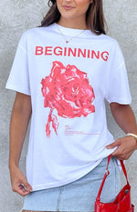 Detail of the white oversized tee featuring red BEGINNING text a pink rose graphic and rosé definition