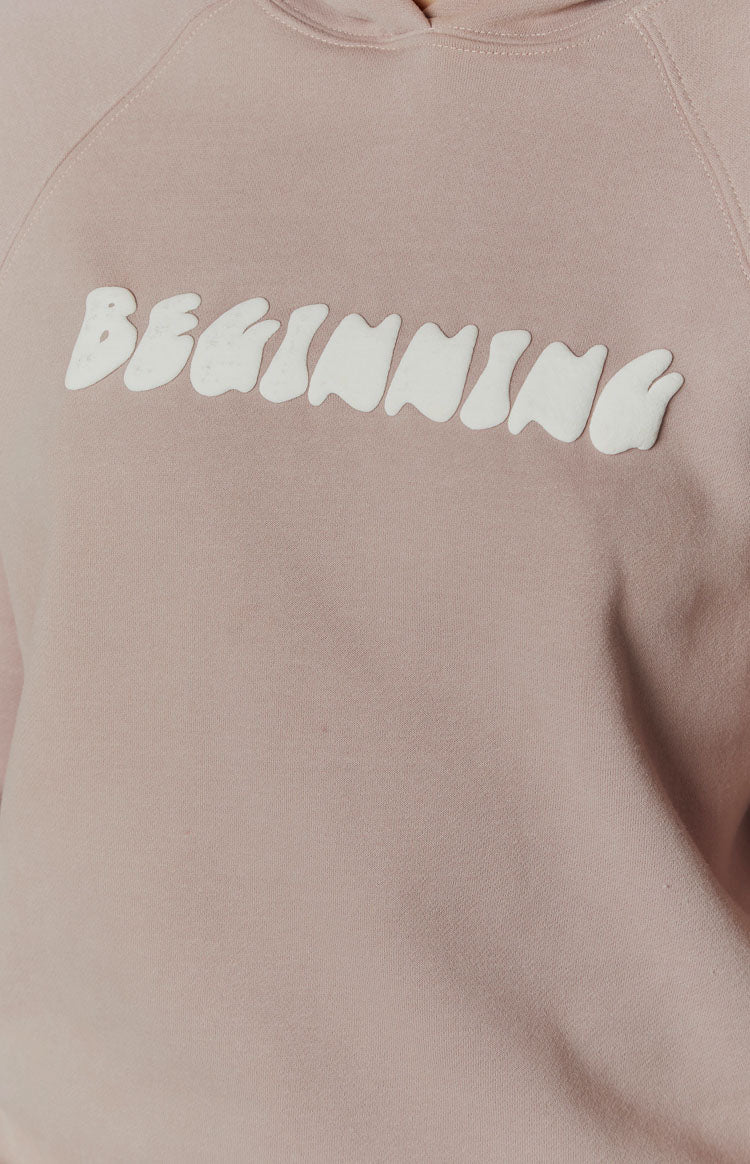 Close-up of the raised bubble-style white BEGINNING text on the beige hoodie