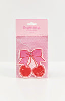 Two cherries with a bow air freshener on car review mirror.