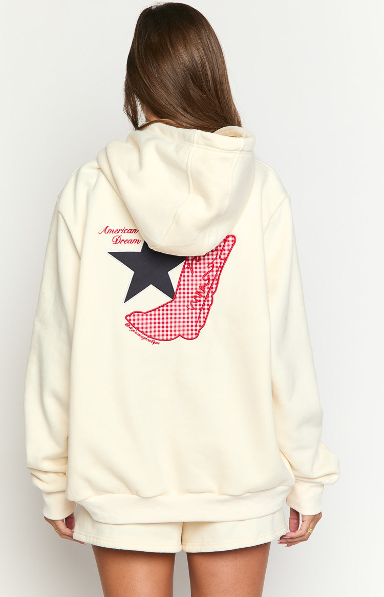Rear view of a cream hoodie with "American Dream" text, a black star, and a red gingham cowboy boot graphic on the back