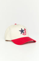 Girl wearing a cream coloured baseball cap with a contrast red brim and embroidered western inspired design