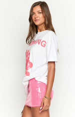Side view of an oversized white tee with short sleeves and a coral pink graphic print