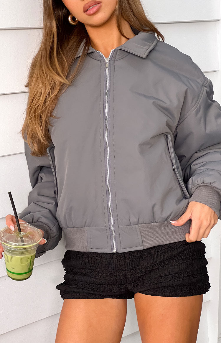 Front view of a grey puffed bomber jacket with a silver zipper, classic collar, ribbed cuffs, and hem