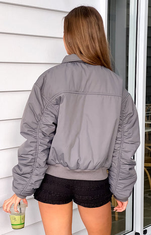 Rear view of a grey puff bomber jacket showing the ruched long sleeves and ribbed hem
