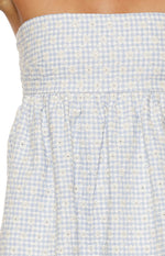 Close-up of the blue and white gingham fabric with white floral embroidery and gathered waist seam