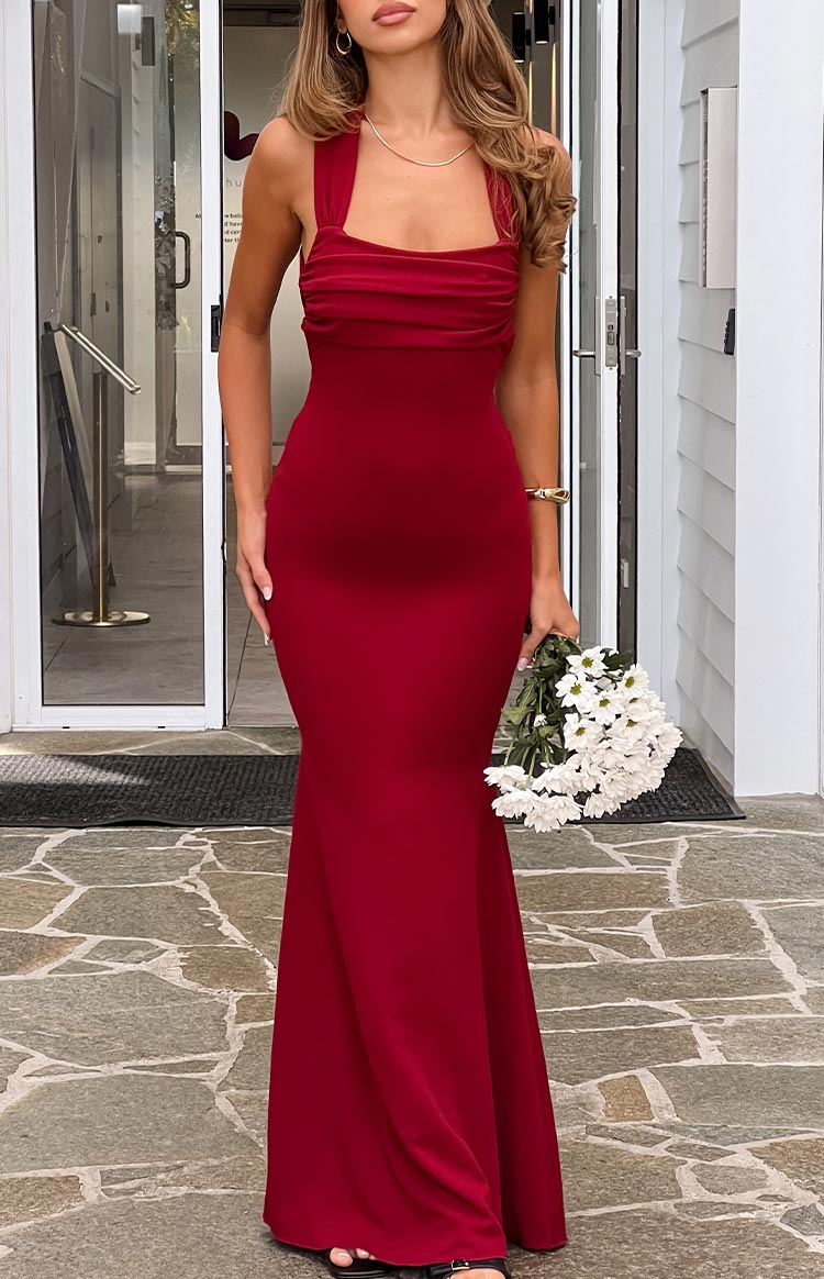 A form-fitting- mermaid-style long gown in a rich wine red- featuring a pleated and ruched strapless bustline with subtle halter-style straps. This elegant dress is suitable for a formal event or gala.