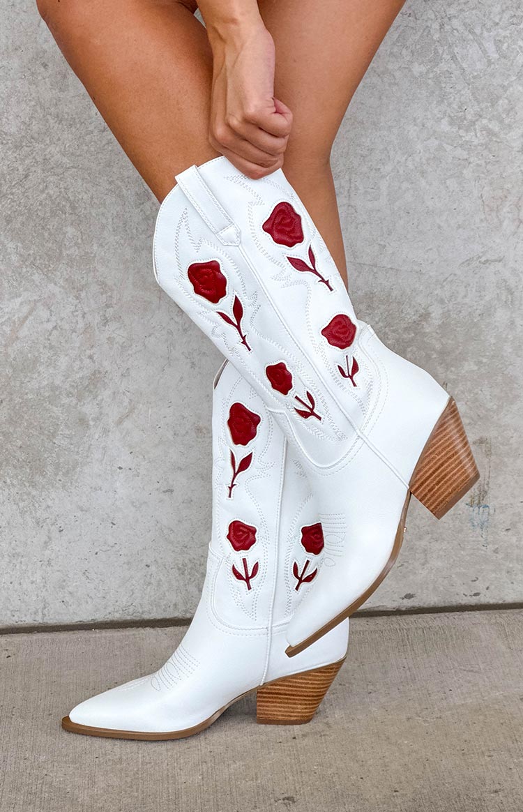 Side view of white cowboy boots with red rose embroidery and a stacked wooden heel