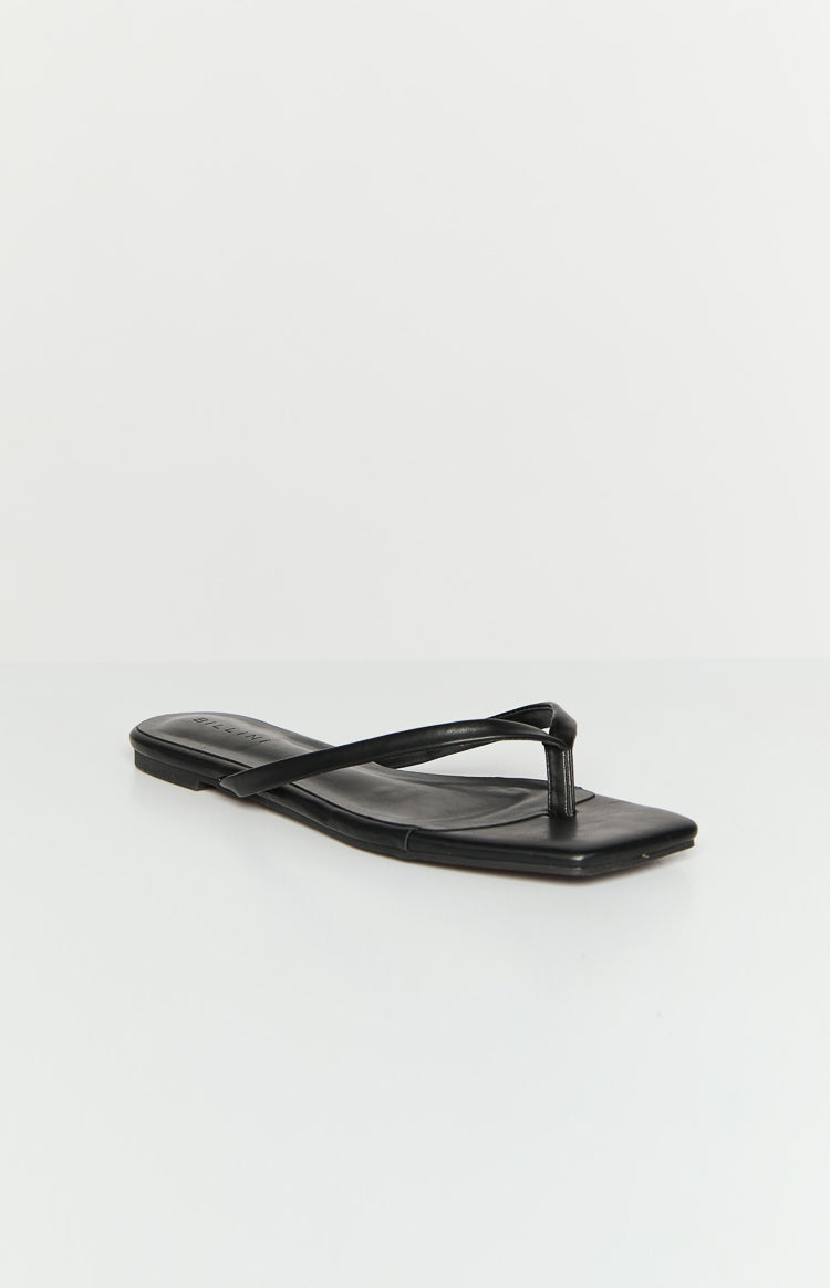 Angled view of a black flat shoe with a square toe and a thin, twisted thong strap