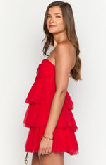 Side view of a red strapless mini dress with a ruched bodice and a tiered ruffled tulle skirt