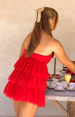 Side view of a red strapless mini dress with a tiered ruffled tulle skirt