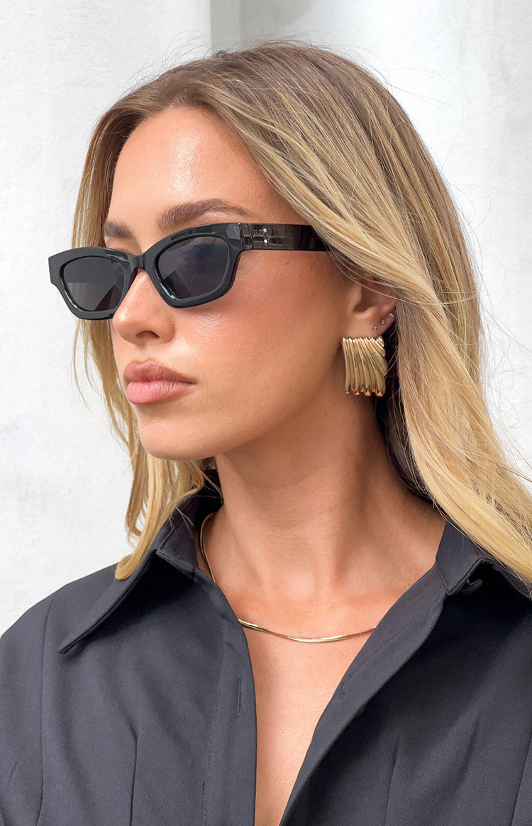 Side view of black slimline sunglasses with a subtle cat-eye shape and thick temples featuring small silver studs