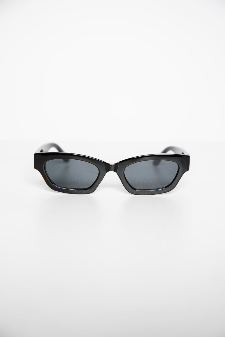 Black slimline sunglasses with dark grey lenses and an angular frame from a slightly elevated perspective