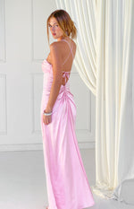 Side view of a pink satin maxi dress with criss-cross tie-back straps and ruched detail