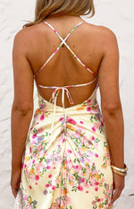 Rear view of a yellow bloom satin maxi dress with criss-cross back straps, a tie detail, and ruched skirt
