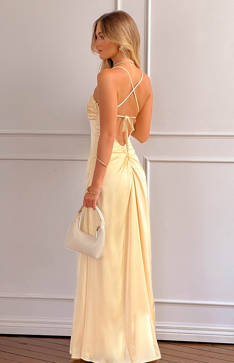 Side view of a yellow satin maxi dress with criss-cross back straps, tie-back, and ruched skirt