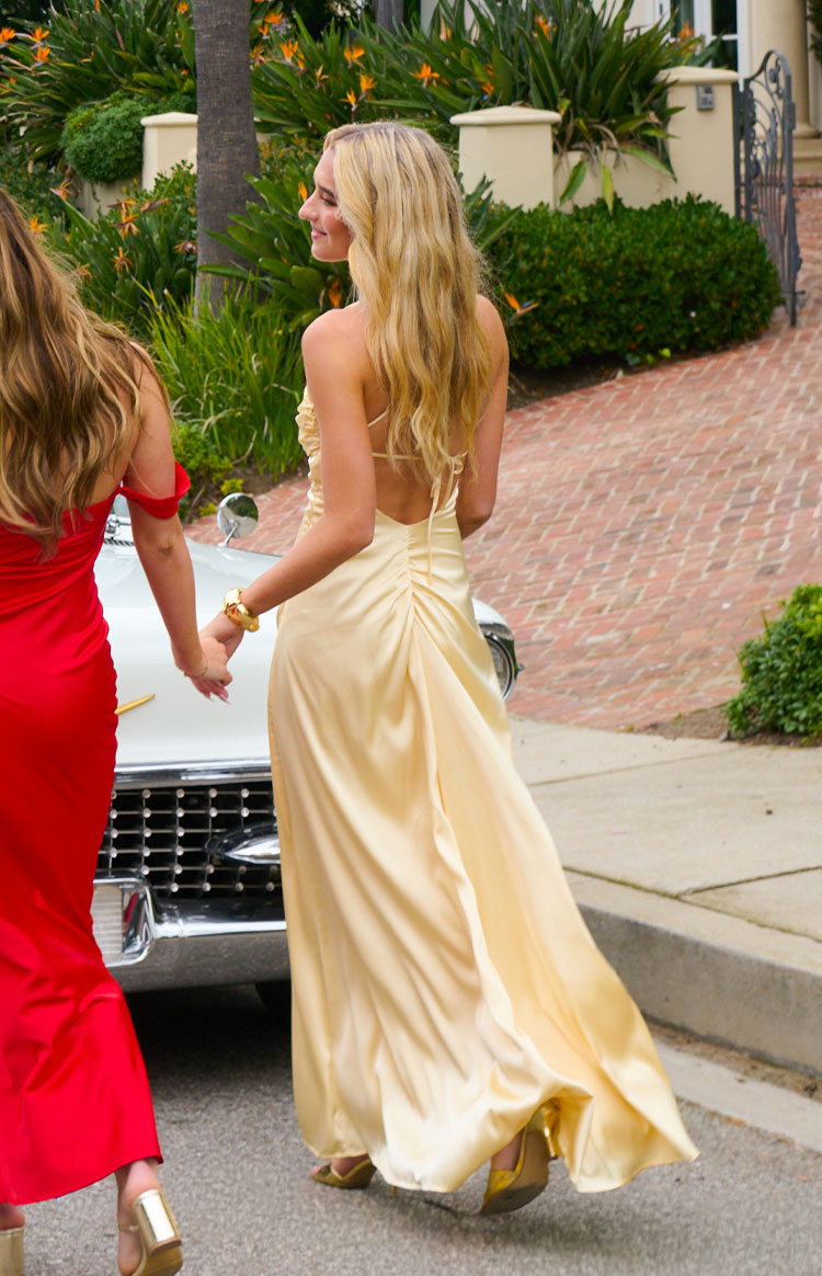 Rear view of a yellow satin maxi dress with a low scoop back, criss-cross tie straps, and ruched skirt
