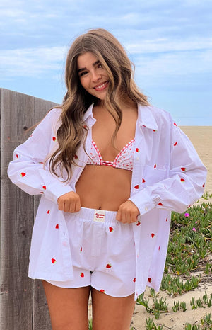 Model is wearing a white oversized long-sleeve shirt with a scattered red strawberry embroidery pattern