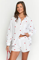 Model is wearing a white oversized long-sleeve shirt with a scattered red strawberry embroidery pattern