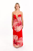 A bright red strapless maxi dress adorned with large orange hibiscus floral prints- featuring a deep U-shaped neckline- suitable for a striking resort or summer event.