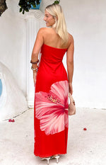 Rear-side view of the red strapless maxi dress with a large pink hibiscus print on the flowing skirt