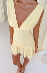 Yellow mini dress with a deep V-neck, ruched bodice and skirt, and a ruffled hemline