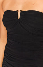 Close-up of the black strapless dress showing the gold sphere detail at the V-cutout neckline and ruched bodice