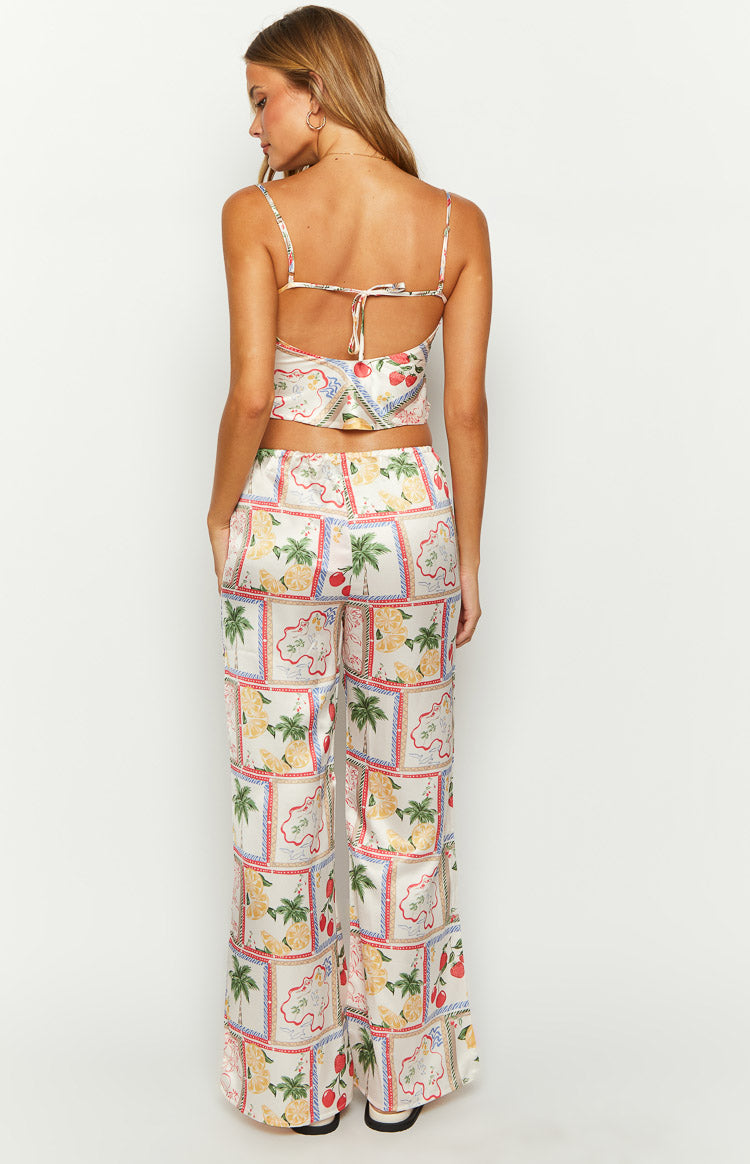 Close-up of the white satin pants with a colorful Roma print featuring palm trees, lemons, and strawberries in bordered squares