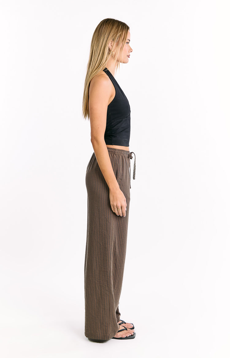 Side view of relaxed brown vertical stripe pants with a drawstring waist