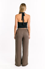 Rear view of brown wide-leg pants with thin dark vertical stripes and an elasticated waistband