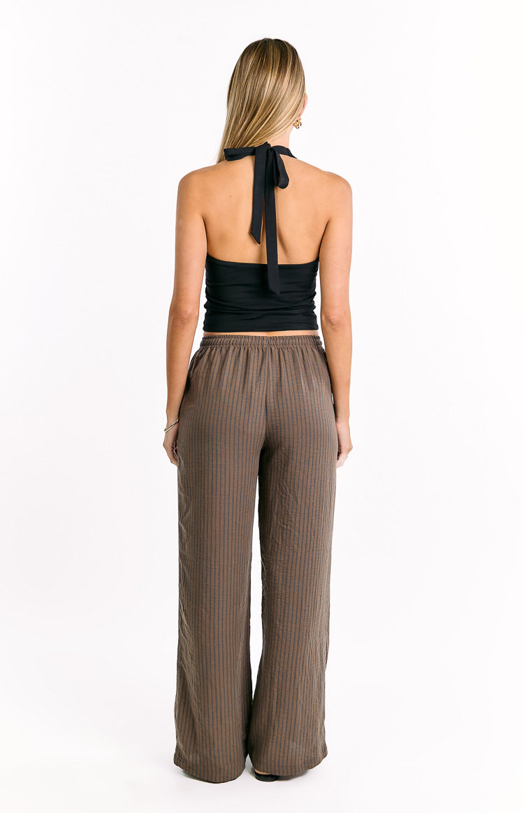 Rear view of brown wide-leg pants with thin dark vertical stripes and an elasticated waistband