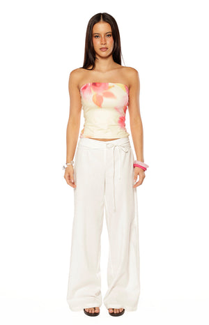 Our model wearing a strapless top in a creamy white fabric with a blurred abstract floral print in shades of pink and coral.