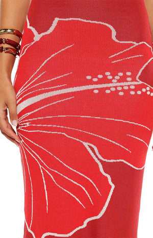 Model wears the Carly Red Knit Maxi Dress featuring a bold hibiscus print. This bodycon dress is a stunning choice for a summer vacation or beach party.