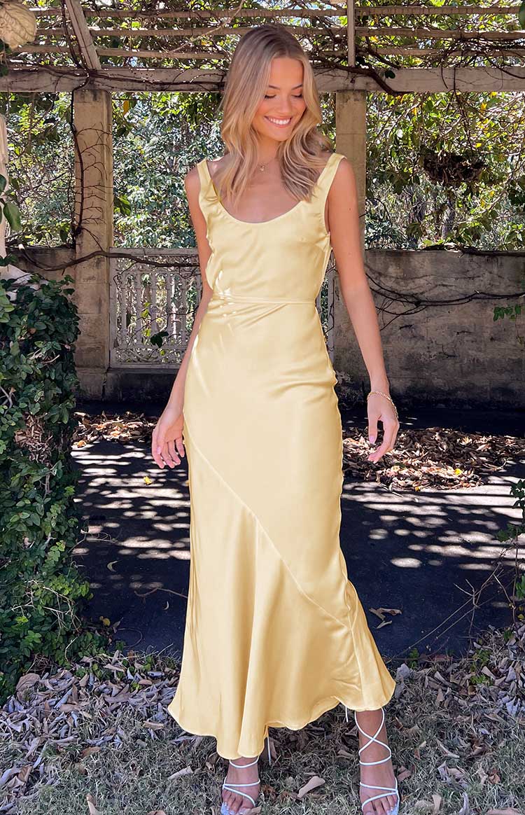 Close-up of the smooth carnation yellow satin fabric of the maxi dress