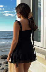 Back view of a black chiffon top with ruffled shoulder straps and a long tie detail at the side