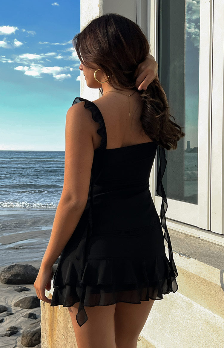 Back view of a black chiffon top with ruffled shoulder straps and a long tie detail at the side