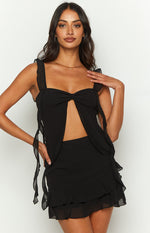 Close-up of the black chiffon top showing the twisted bust detail, midriff cutout, and ruffled shoulder straps