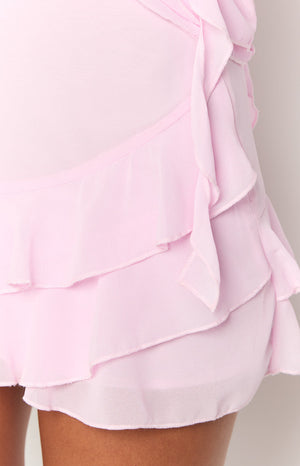 Close-up of the pink chiffon mini skirt showing the layered ruffles and side tie detail