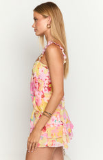 Side view of a vibrant pink and yellow floral print top with ruffled shoulder straps and a relaxed, flowy fit