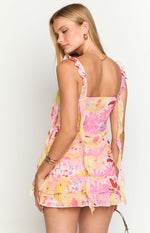 Rear view of a pink and yellow floral print top with ruffled shoulder straps and tiered ruffle hem