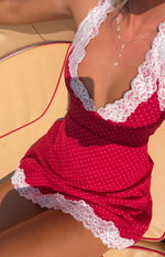 Close-up of the red polka dot mini dress with a deep V-neckline and hem trimmed with white lace