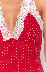 Close-up of the deep V-neckline with white lace trim and gathered bust detail on the red polka dot dress