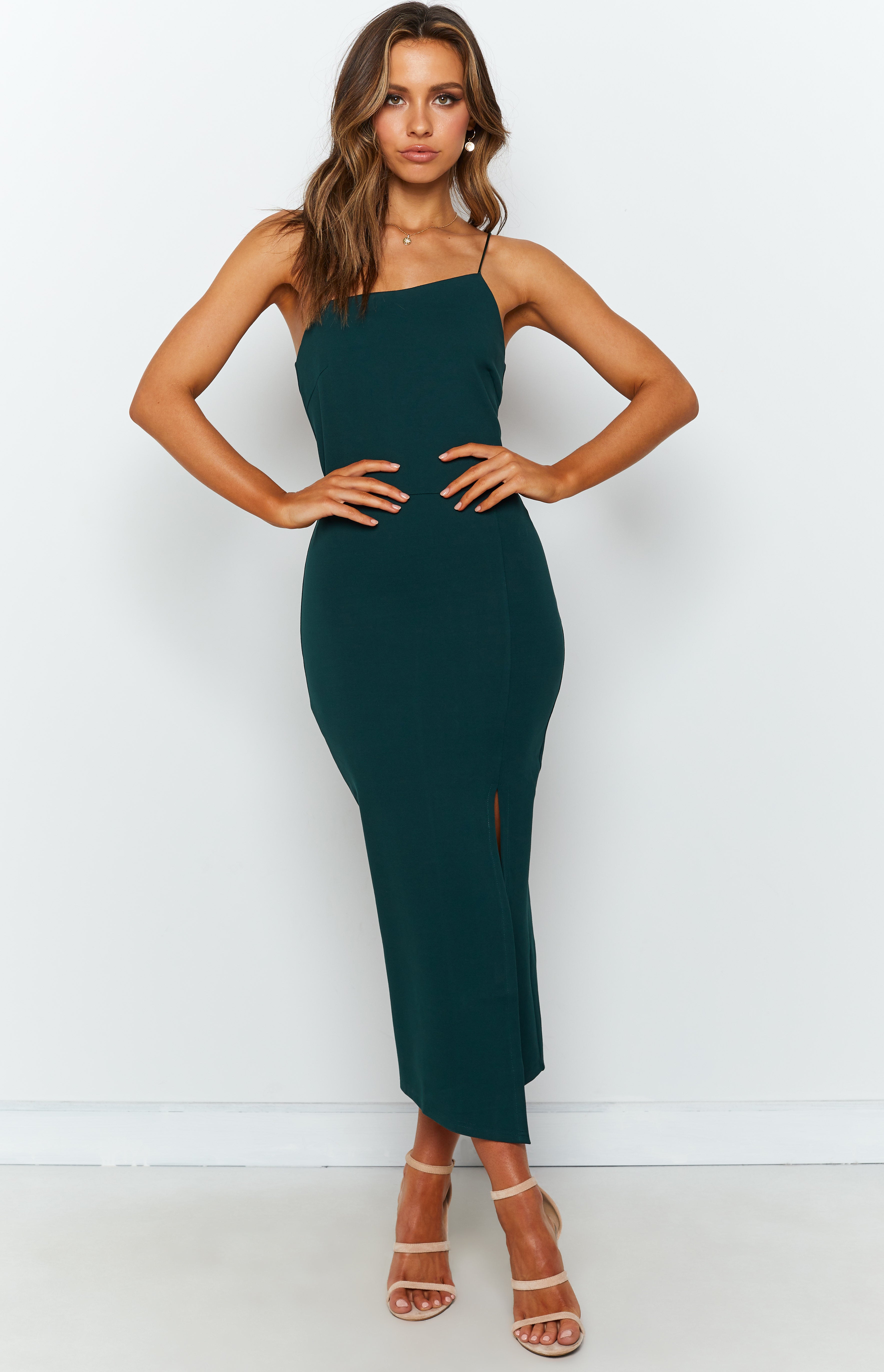 Emerald green bodycon midi dress with an asymmetrical neckline, thin spaghetti straps, and a high side split