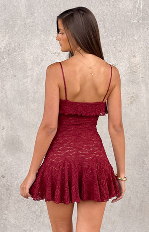 back angle of a woman wearing a deep red lace mini party dress with a flowy skirt and layered top hem - perfect for festivals and country concerts